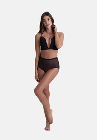 Reggiseno nero a scollatura profonda con spalline regolabili, abbinato a slip neri a vita alta e semitrasparenti, che mettono in mostra un materiale liscio e un design elegante.