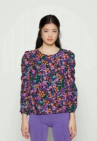 Camisola de manga longa em tecido preto com um padrão floral colorido em roxo, laranja e verde. Mangas bufantes com detalhes franzidos.