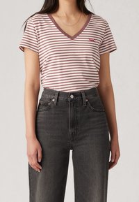 Striped t-shirt in soft cotton with a v-neck and short sleeves; features pink and white stripes and a small red Levi's logo on the chest.
