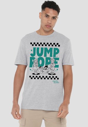 A young man wears a gray t-shirt featuring a retro "Jump Rope" graphic with children playing and the "Squid Game" logo at the bottom.