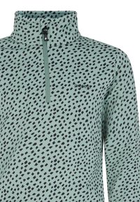 Pullover verde chiaro con colletto alto e motivo a pois neri irregolari. Presenta una mezza zip e un piccolo logo sul petto.