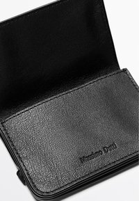 Czarny portfel ze skóry o teksturowanej powierzchni, z gładkim wnętrzem i tłoczonym logo. Smukły design z minimalistycznymi elementami metalowymi.