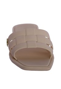 Sandalia beige de tipo fácil de poner con diseño de tiras trenzadas, suela plana y forma de punta cuadrada. Fabricada en material sintético suave, con detalles en hardware dorado.