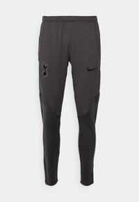 Pantalon de sport gris avec une coupe près du corps, taille élastique, poches latérales et accents noirs texturés avec un logo sur le côté gauche.