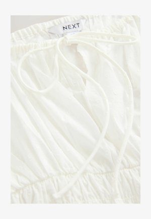 Vit, lätt tyg med texturerade prickmönster. Har en samlad elastisk midja och en dragsko. Märkt med "NEXT."