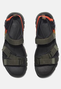 Green and black sandals featuring adjustable straps in gray and orange, rubber soles, and a textured insole for grip and comfort.
