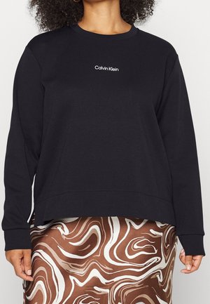Schwarzer Sweatshirt mit langen Ärmeln und rundem Halsausschnitt, mit einem weißen "Calvin Klein" Logo in der Mitte. Glattes Material, lockere Passform.