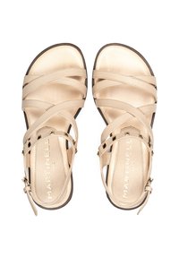 Sandalias de cuero beige con múltiples correas entrelazadas, suela plana y cierre de hebilla lateral. Presenta sutiles acentos metálicos y logo.
