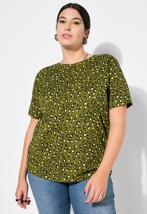 Olivgrünes T-Shirt mit schwarzem und gelbem Leopardenmuster, kurze Ärmel, runder Ausschnitt, weicher Stoff, lockere Passform, kombiniert mit blauen Jeans.