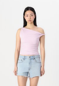 Top de un solo hombro en rosa claro, hecho de tela elástica; diseño ajustado con textura fruncida, combinado con shorts de mezclilla de lavado claro con dobladillo deshilachado.