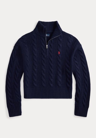 Tengerészkék keresztszemes kötött gyapjú pulóver fél cipzárral, bordázott mandzsettákkal és szegéllyel, valamint kis piros hímzett logóval a bal mellrészen.