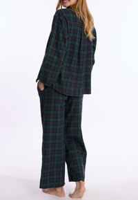Groen en marineblauwe geruite pyjama set met een shirt met knopen en losse broek. Zacht materiaal, lange mouwen en zakken in de broek.