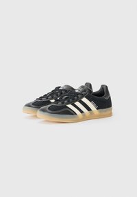 Zwart-witte Adidas Gazelle sneakers met een rubberen zool, met een gestructureerde stof en het traditionele drie-strepen ontwerp.