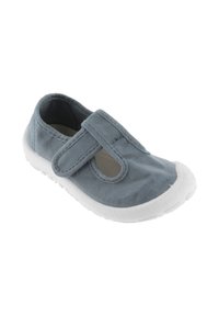 Zapato de lona gris con una suela de goma blanca, que cuenta con una correa de velcro y detalles laterales recortados para facilitar la transpiración.