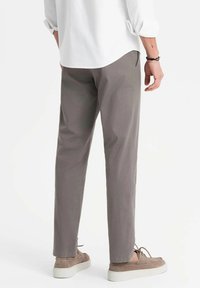 Pantaloni di cotone grigi con un design a gamba dritta, caratterizzati da una sottile texture e tasche laterali, abbinati a scarpe casual di colore chiaro.