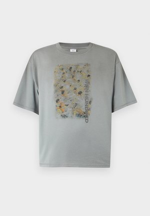 Harmaa ylisuuri T-paita, jossa haalistunut abstrakti väkijoukkoaihe ja pystysuora "WON HUNDRED" -teksti edessä keskellä.