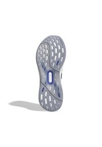Suela de zapato con un acabado translúcido gris, que presenta una banda de rodadura decorada con segmentos de goma blanca y azul, y un corte ovalado en el centro.