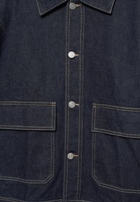 Giacca di jeans scura con bottoni a pressione argentati, colletto e doppie tasche frontali con dettagli di cucitura visibili. Texture liscia.