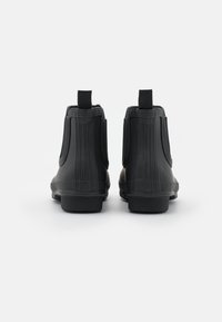 Bottes de cheville en caoutchouc noir avec des nervures verticales, des panneaux latéraux élastiques et des languettes à l'arrière pour un enfilage facile. Semelles plates.