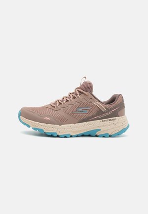 Zapatilla de running en rosa suave con parte superior de malla transpirable, media suela beige y suela azul. Presenta un talón reforzado y un diseño acolchado.