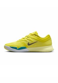 Gelbe Sportschuhe mit einem strukturierten Obermaterial, ausgestattet mit einem grauen Swoosh, türkisfarbenen Akzenten und einer weißen gemusterten Sohle für besseren Halt.