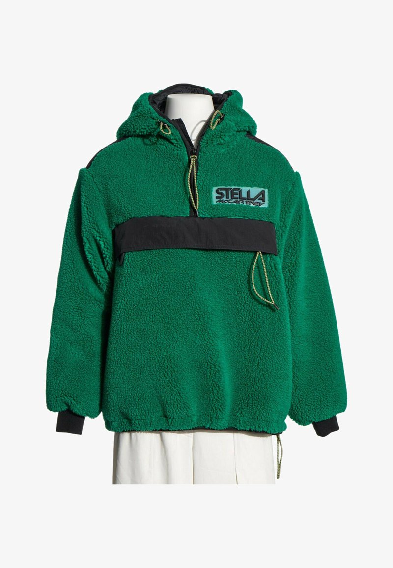 Sweat à capuche en polaire verte avec poche poitrine noire, cordons et logo Stella McCartney sur le devant, présenté sur un mannequin blanc.