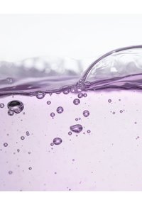 Paarse vloeistof met bubbels van verschillende grootte. Het oppervlak vertoont een zachte golving en heeft een lichte en gladde textuur. De achtergrond is wit.