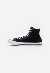 Czarne sneakersy za kostkę wykonane z płótna, z białymi oczkami, sznurowadłami oraz gumową podeszwą z teksturowanym noskiem i kontrastującymi paskami.