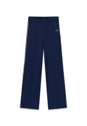 Granatowe spodnie z szerokimi nogawkami, białe paski po bokach oraz logo "GUESS" na górnej lewej uda, elastyczna talia i detale szwów z przodu.
