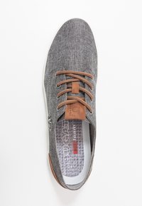 Grå tygsneaker med bruna läderdetaljer, med rund tå, snörningsdesign och mönstrad innersula. Platt gummisul.