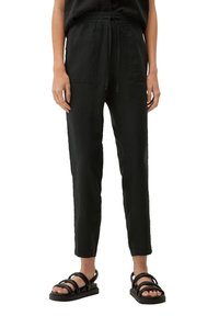 Svart, lätt, taperade byxor med elastisk midja, två framfickor och avslappnad passform, ihop med svarta sandaler.