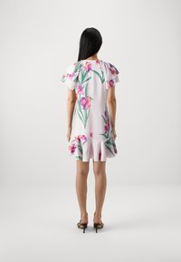 Robe florale avec des manches courtes à volants, ornée d'orchidées roses et de feuilles vertes, sur un fond de couleur claire, avec un ourlet évasé.