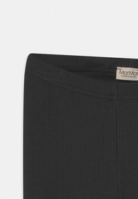 Svart ribbede leggings med en myk tekstur og elastisk midje. Har et synlig merke som er sydd inn i midjen.