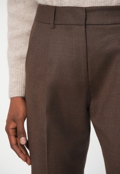 Καφέ ταιριαστά παντελόνια φτιαγμένα από υφασμάτινη υφή, με επίπεδο μέτωπο, πλαϊνές τσέπες και λείο ελαστικό.