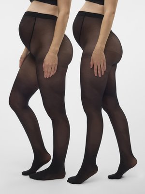 To gravide kvinner som står side om side, iført svarte gjennomsiktige graviditetstrømpebukser og svarte crop tops mot en hvit bakgrunn.