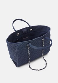Torebka tote w kolorze granatowym, pikowana, z podwójnymi uchwytami z materiału oraz akcentem w postaci łańcucha. Wnętrze zawiera kieszeń na zamek oraz zapięcie na magnes.