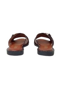 Sandali in pelle marrone con due ampie cinghie, suola piatta e superficie liscia. Le sole interne sono marroni con un logo sottile.