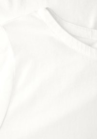 Tessuto di cotone bianco con una texture liscia, dotato di un classico collo rotondo e maniche corte. Sottile dettaglio a coste.