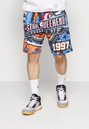 Nogi w kolorowych szortach do koszykówki NBA All-Star Weekend Cleveland '97, białych skarpetach za kostkę i czarno-białych butach do koszykówki.