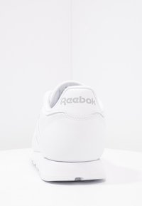 Vit Reebok-sneaker sedd bakifrån som visar varumärkeslogotypen på hälkappan och en ren, minimalistisk design.
