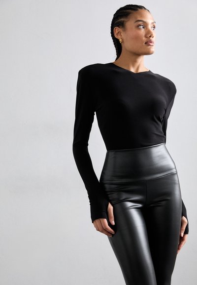 Sort langærmet top med en tætsiddende pasform, parret med højtaljede sorte leggings i kunstlæder med en glat tekstur og et strømlinet udseende.