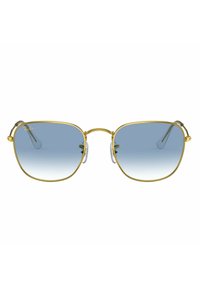 Occhiali da sole in metallo dorato con montatura quadrata, lenti blu sfumate, cuscinetti nasali trasparenti e cerniere. Presenta una marca minimale nell'angolo superiore sinistro della lente.