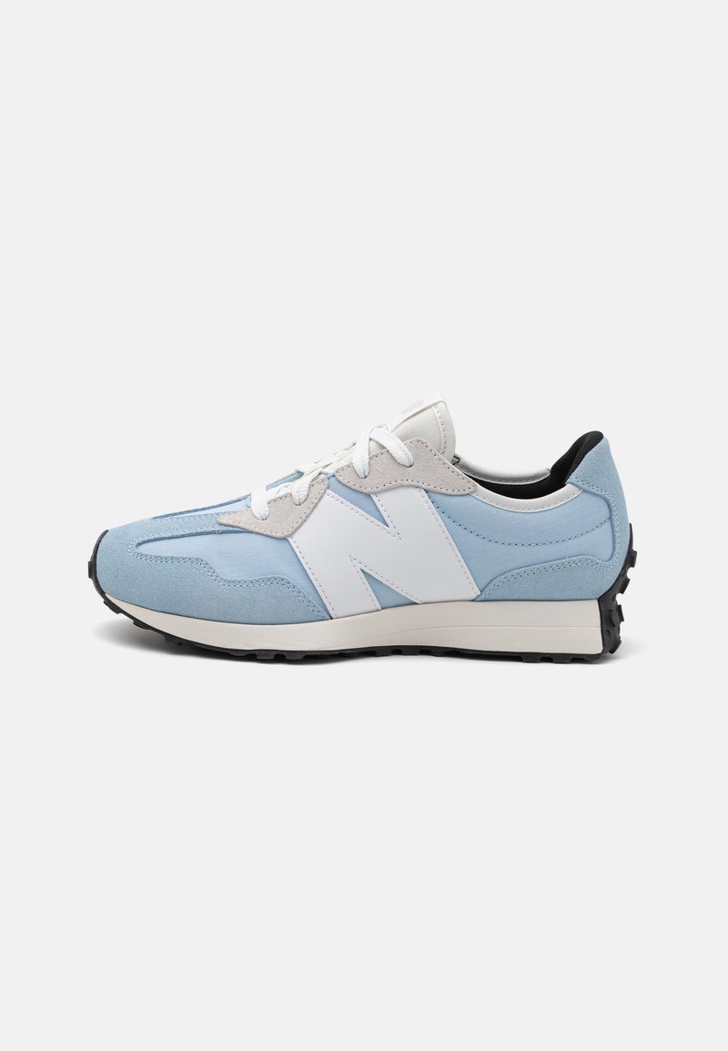 Light blue and white suede sneaker with a black outsole, featuring a large white "N" logo, flat laces, and textured details on the upper.
