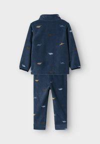 Ensemble de pyjama en polaire bleu marine comprenant un haut à manches longues et un pantalon assorti, orné de motifs de dinosaures multicolores.