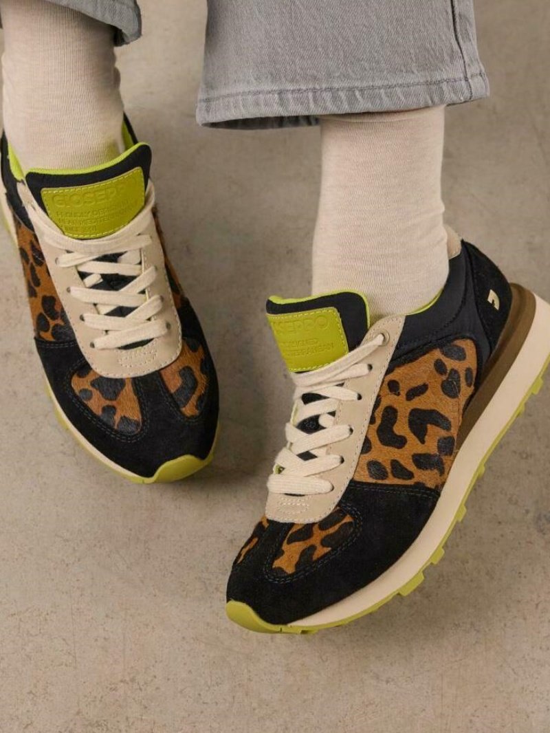 Zapatillas con estampado de leopardo negro y marrón, con cordones crema, detalles en verde y una suela acolchada. Cuenta con un material de ante texturizado.
