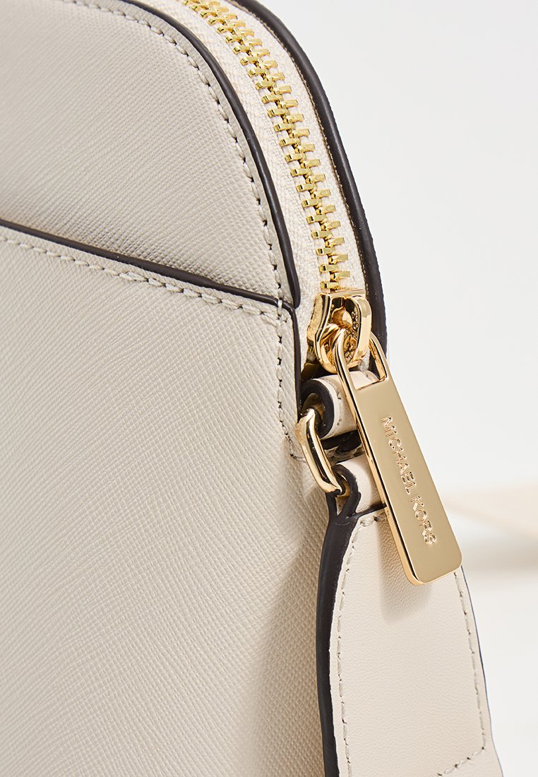 Bolso de mano de imitación de cuero texturizado beige con cremallera dorada y herrajes, que presenta un acento negro alrededor de los bordes y una etiqueta con el logotipo.