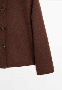 Cappotto marrone in misto lana con una texture liscia, caratterizzato da un taglio dritto, maniche lunghe e quattro bottoni neri sul davanti.