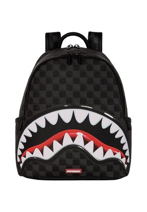 Zaino nero a quadri con una bocca aperta di squalo rossa grafica e denti bianchi affilati sulla tasca frontale, doppie cerniere e spallacci imbottiti.