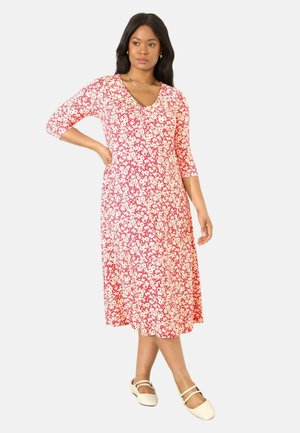 Robe midi rouge à fleurs avec des manches trois-quarts, un décolleté en V et une coupe décontractée. Le motif présente de petites fleurs blanches sur un fond vif.