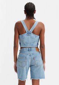 Ljusblå denimcropp med breda axelremmar och stängning bak, i kombination med matchande högmidjade shorts med fransade fållar och fickor.